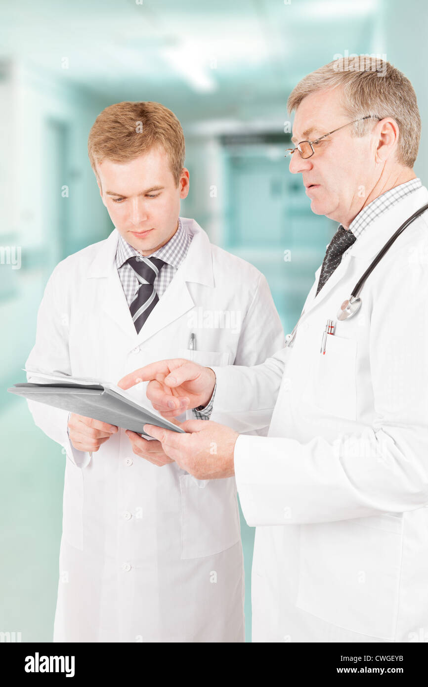 Two medical doctors filling out some form in hospital next to ...