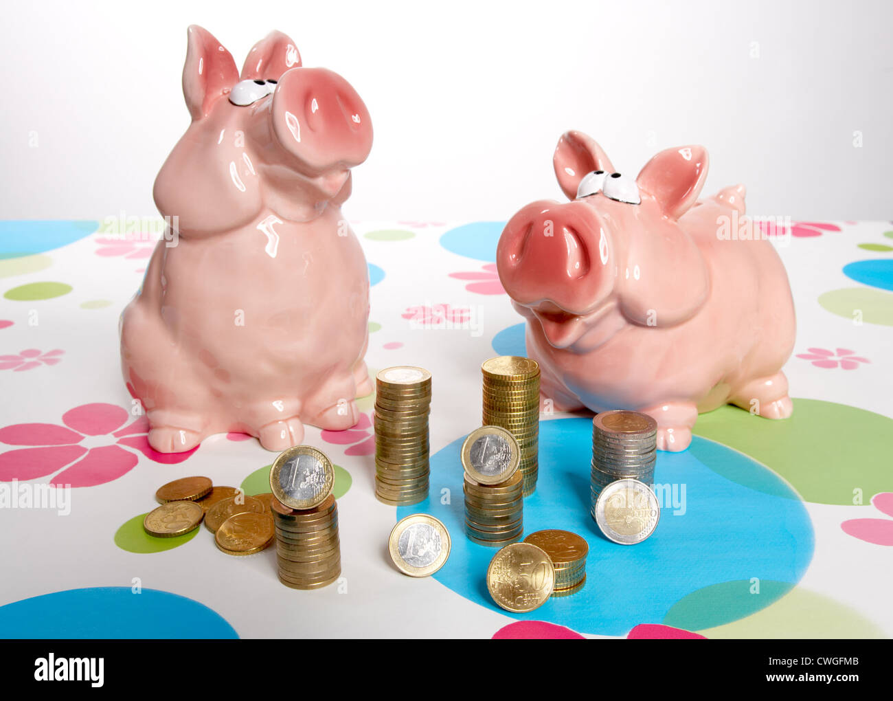 Piggy banks with Muenzstapeln on patterned background Stock Photo