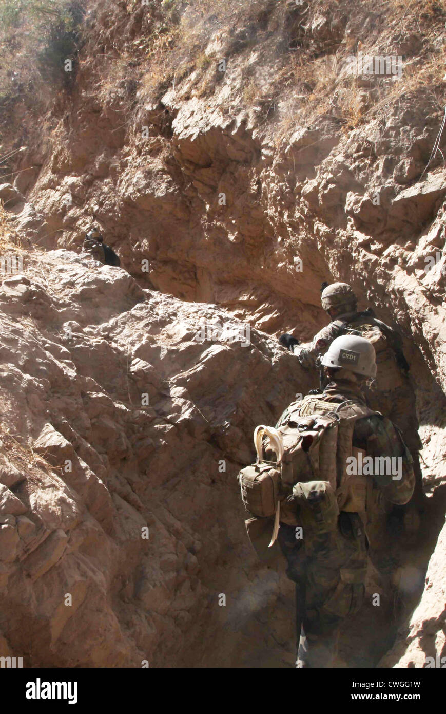 US special operations forces pursue an insurgent through a ravine during a clearing operation September 13, 2011 in Kishim district, Babakashan province, Afghanistan. With the support of special operations forces, Afghan National Army commandos clear a village to disrupt insurgent activity. Stock Photo