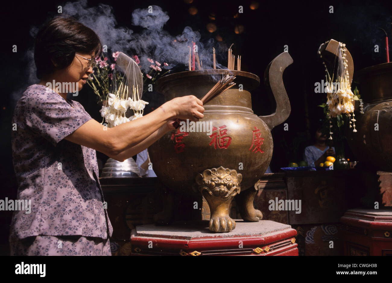 Woman with burning incense sticks in a Taoist temple Stock Photo