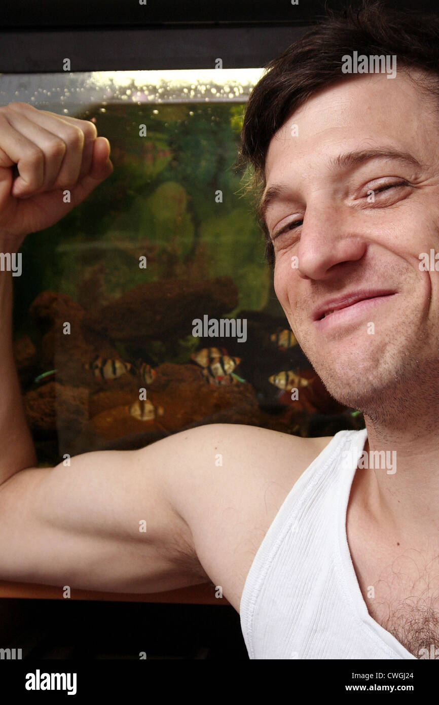 Smiling young man can play in front of an aquarium, the muscles Stock Photo