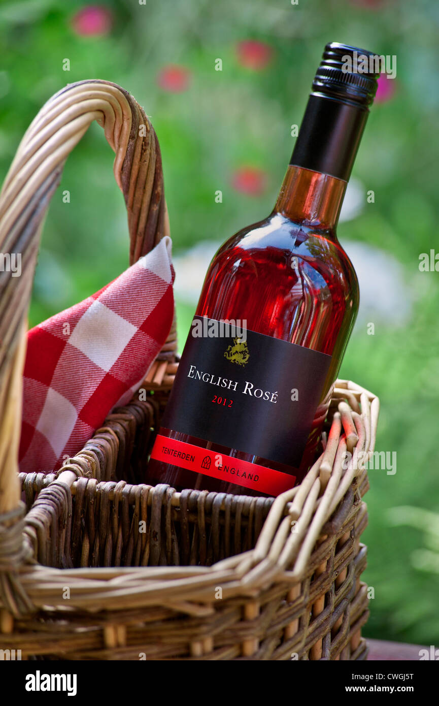 English Rose wine bottle and wicker basket in garden picnic situation Stock Photo