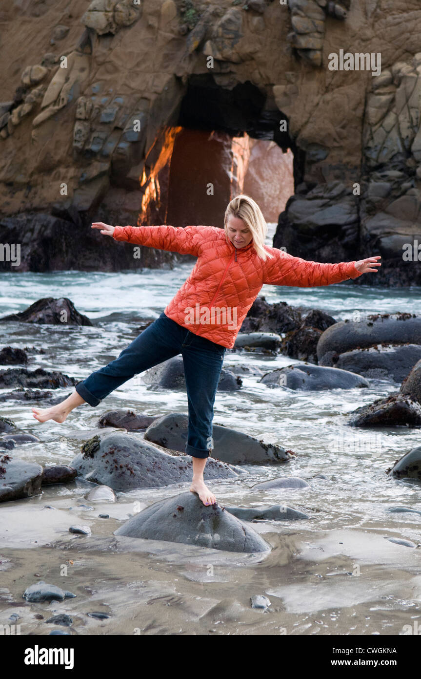 A woman balancing on rock near a blow hole, Big Sur, California. Stock Photo