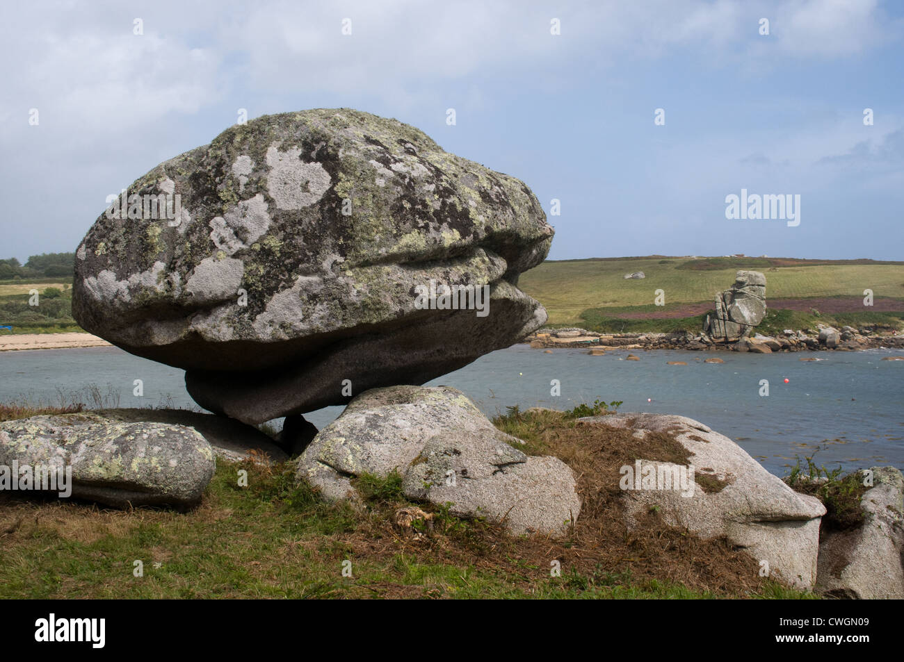 A large boulder balances on smaller rocks on the edge of Porth Hellic , St Mary's, Isles of Scilly Stock Photo