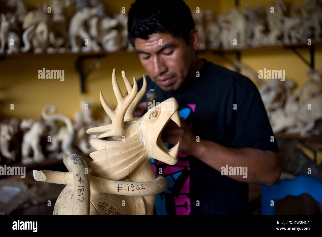 An artist works in a wooden sculpture of a fantastic animal in San Martin Tilcajete, Oaxaca, Mexico, July 13, 2012. Stock Photo
