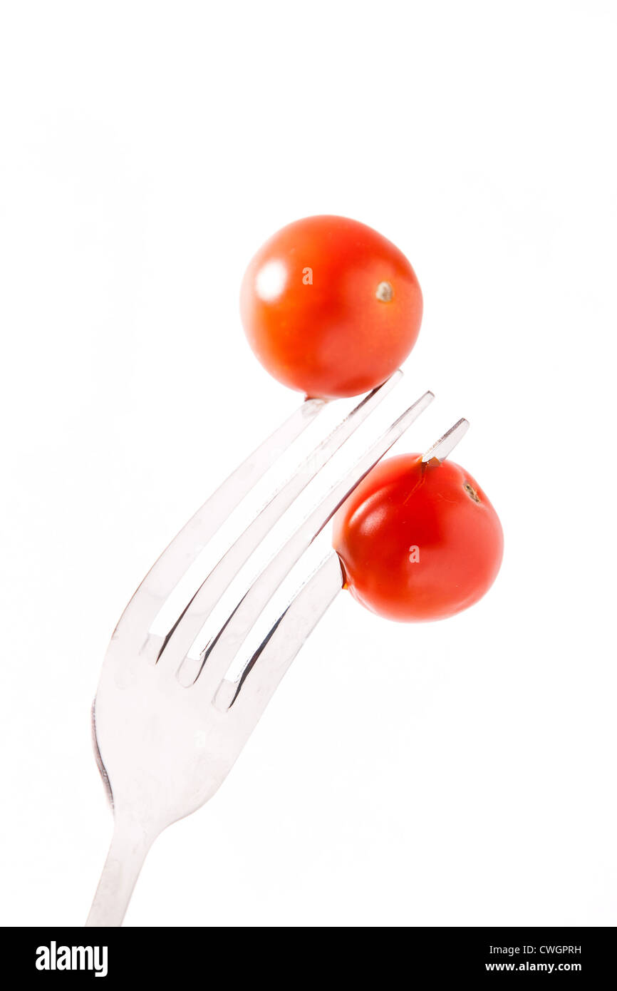 two red tomatos cherry on cogs the fork Stock Photo