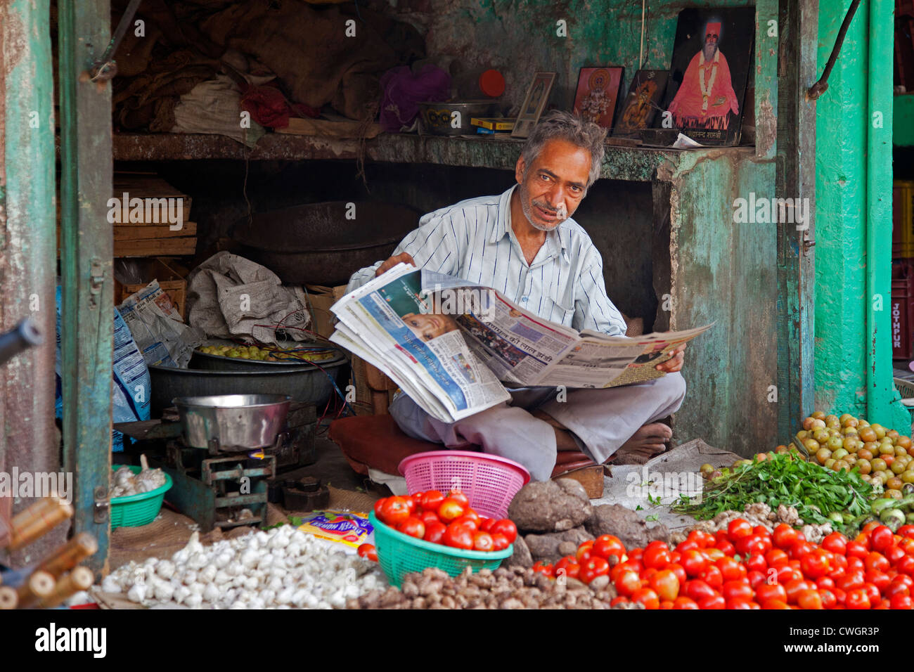Shopkeeper reading newspaper in grocery shop selling vegetables at Jodhpur, Rajasthan, India Stock Photo