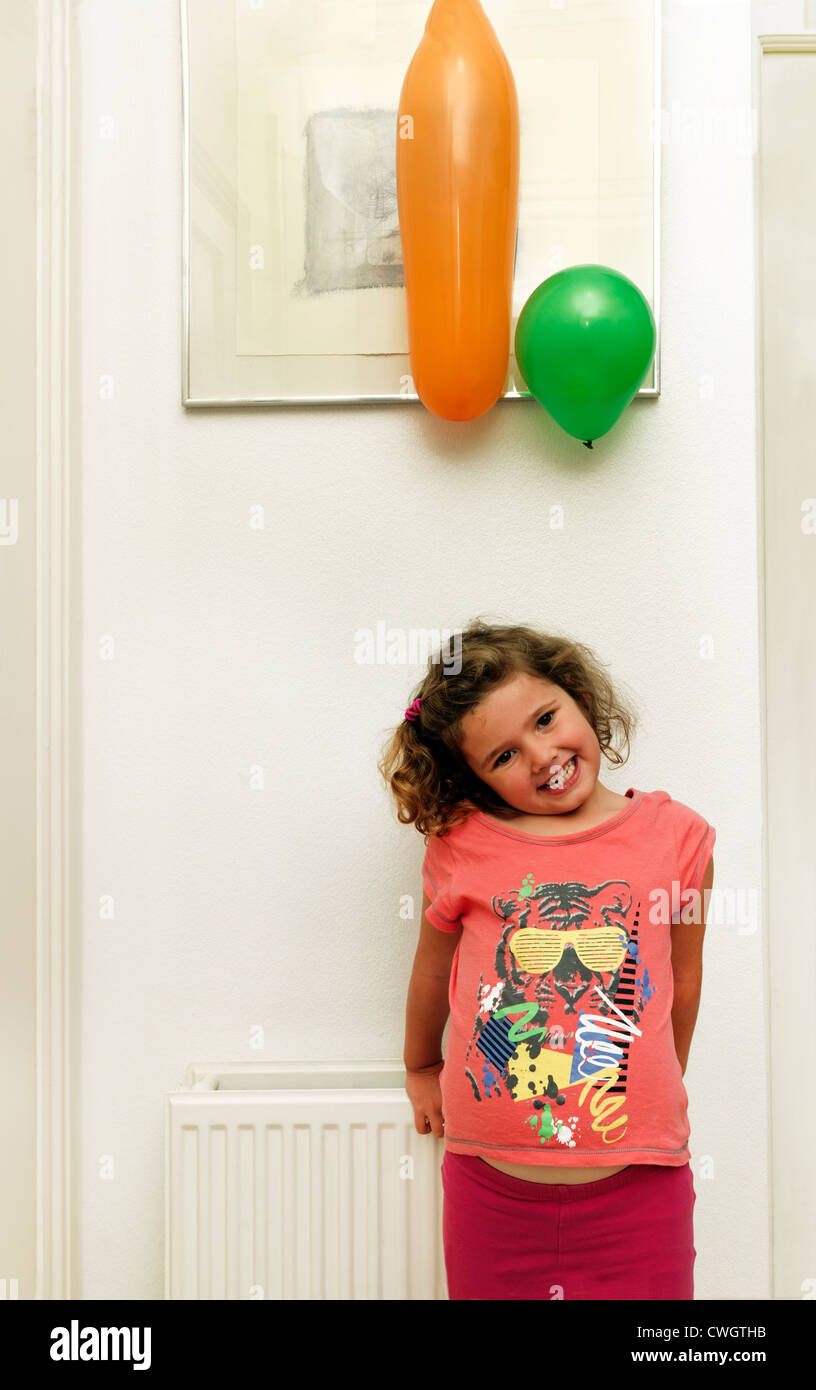 Young Girl Standing By Wall After Rubbing Balloons To Create Static