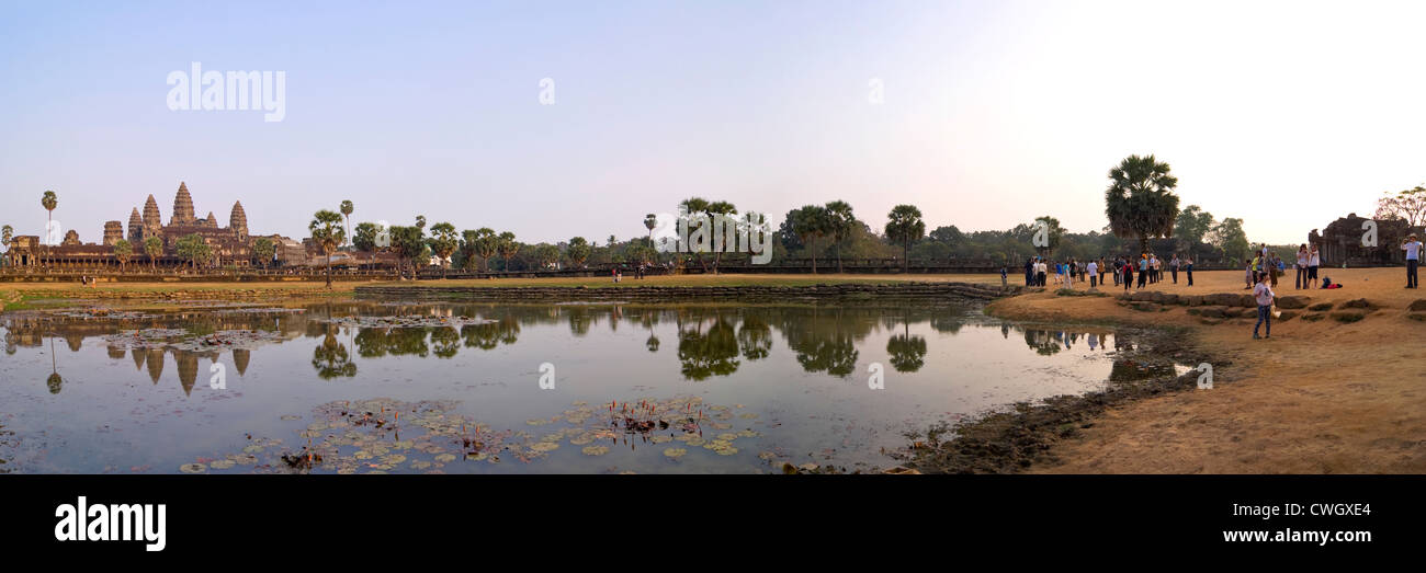 Horizontal panoramic (2 picture stitch) view of the amazing architecture at Prasat Angkor Wat reflected in the water at sunrise. Stock Photo