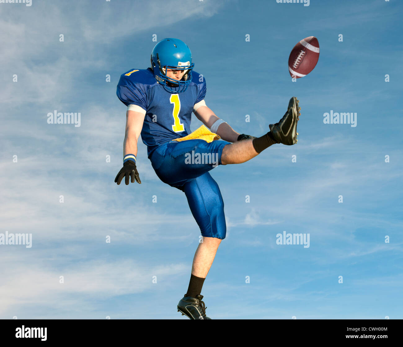 Caucasian football player kicking football Stock Photo