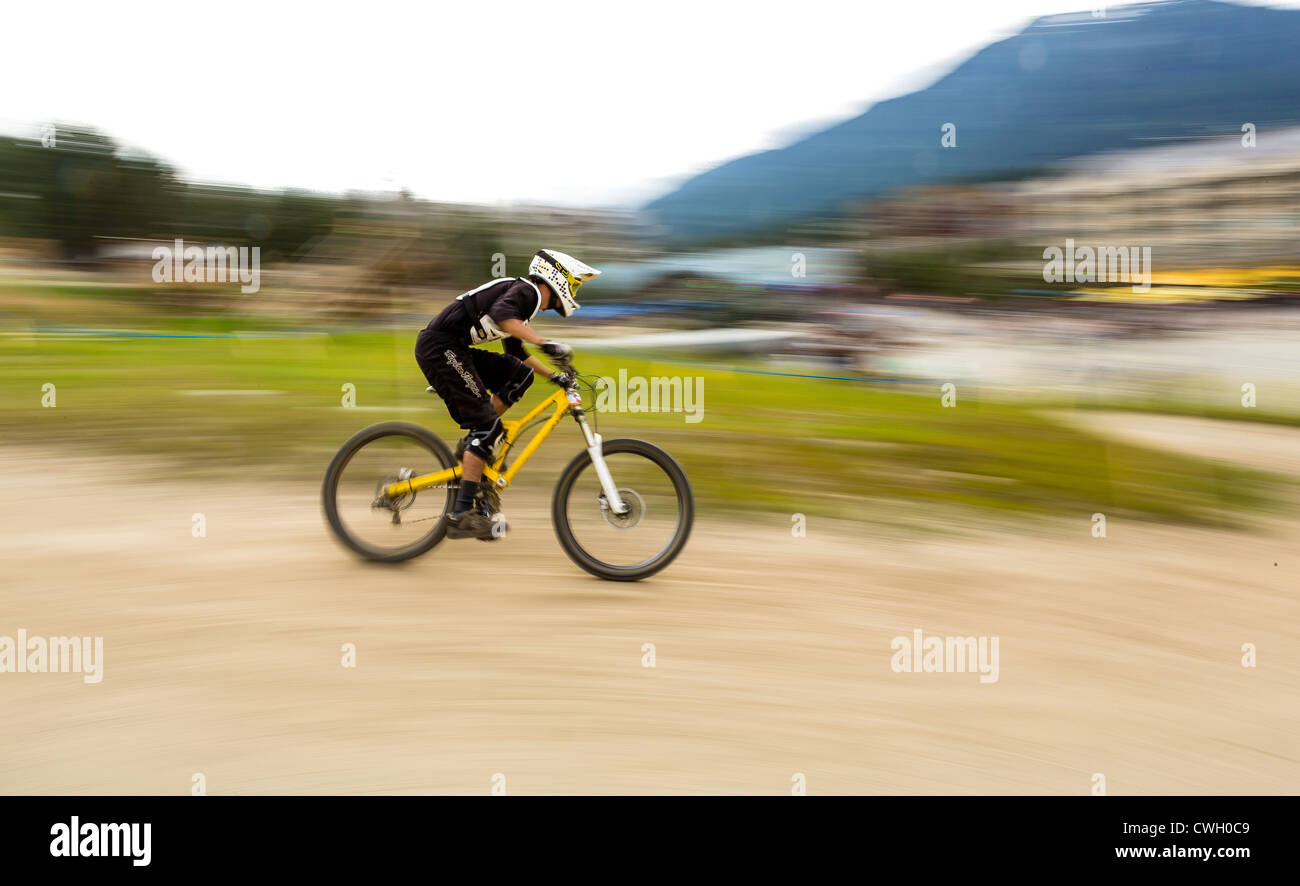 A downhill mountain biker zooms past. Stock Photo