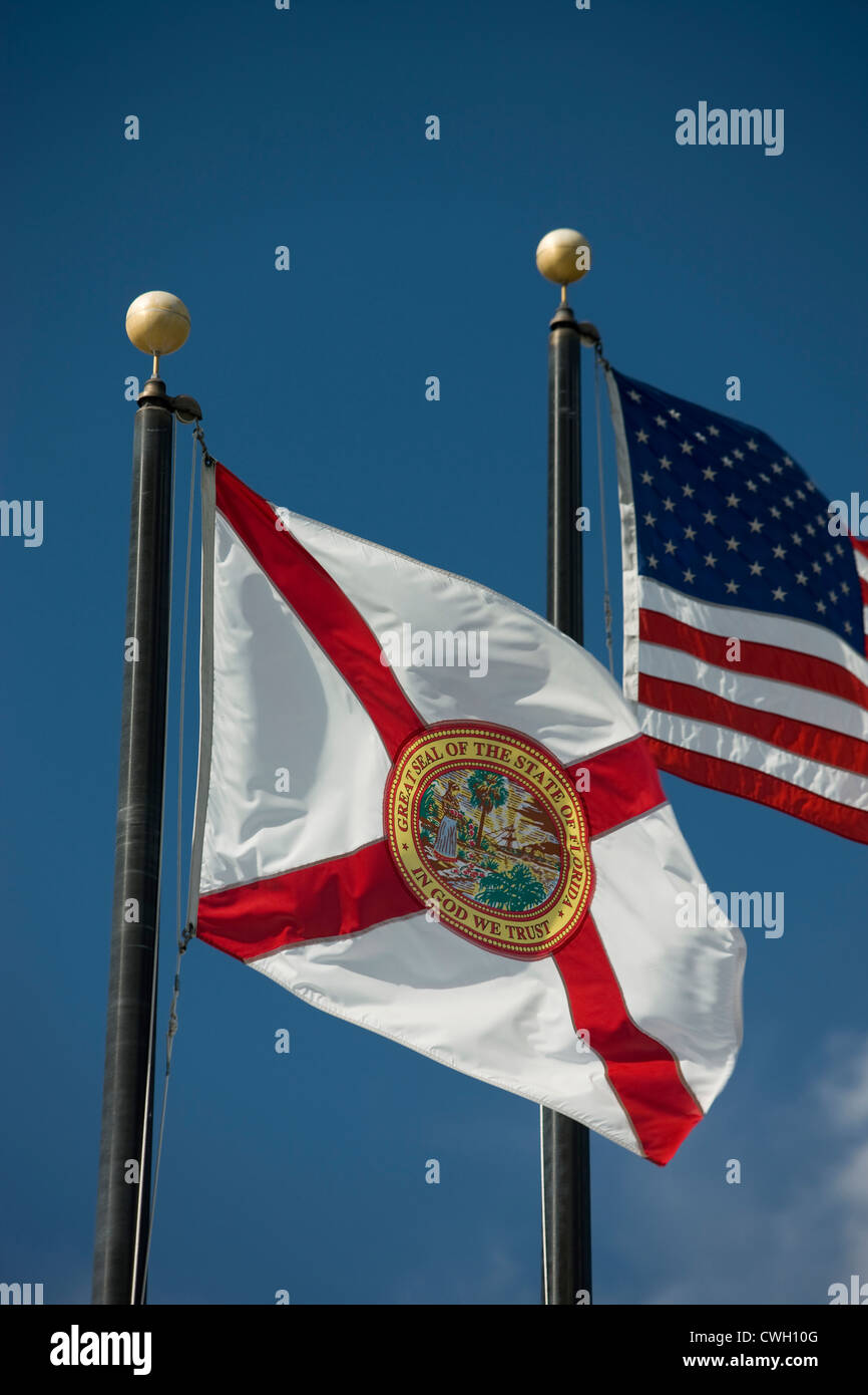FLORIDA STATE FLAG UNITED STATES FLAG FLYING ON FLAGPOLES ON BLUE SKY BACKGROUND Stock Photo