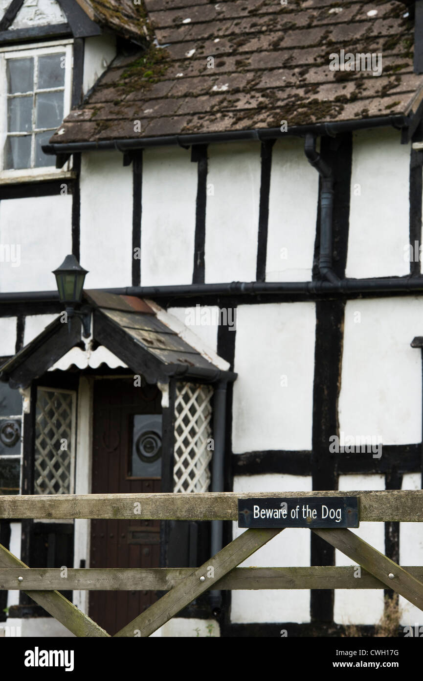 Beware of the Dog sign on a gate in front of an old black and white timber framed house. Herefordshire. England Stock Photo