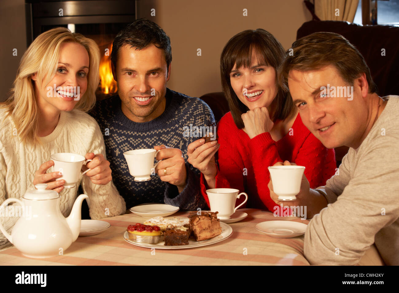 Group Of Middle Aged Couples Enjoying Tea And Cake Together Stock Photo