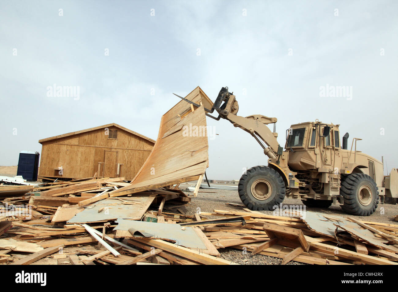 The US Army operates an Armored Combat Engineer Front Loader to demolish a wooden building on Camp Delaram II, Nimroz province, Afghanistan May 15, 2012. Soldiers demolished the building as part of the demilitarization process of the Camp. Stock Photo