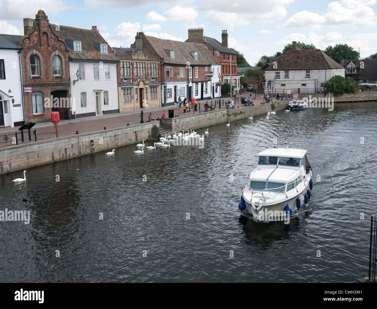 The River Great Ouse at St Ives Cambridgeshire UK showing the quayside and people enjoying the summer with a pleasure boat passi Stock Photo