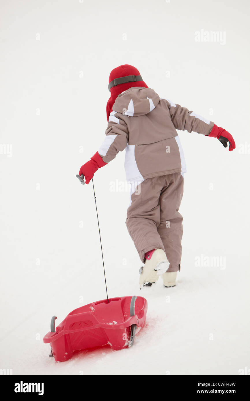 Back View Young Girl Pulling Sledge On Ski Holiday In Mountains Stock Photo