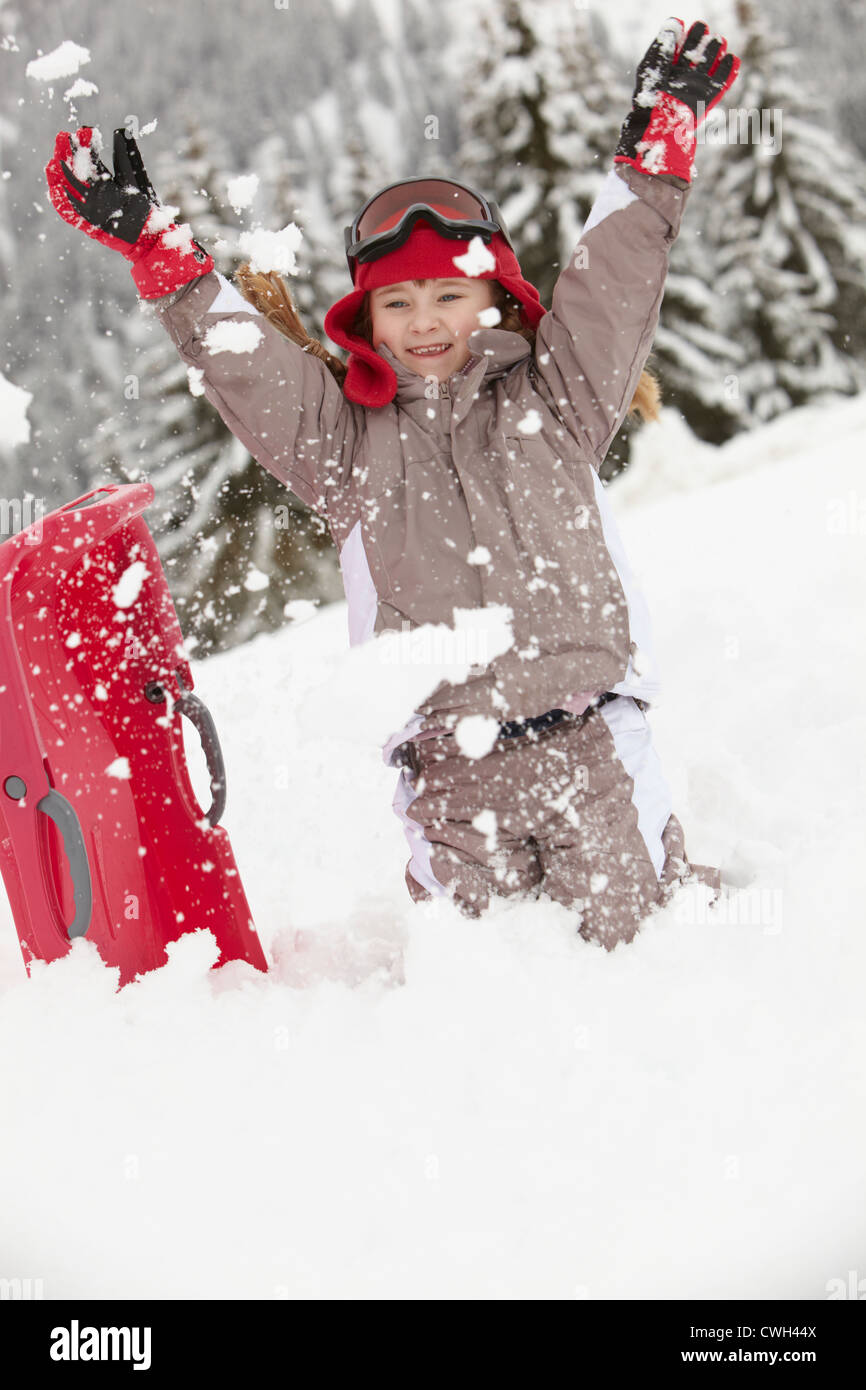 Young Girl Playing In Snow With Sledge On Ski Holiday In Mountains Stock Photo