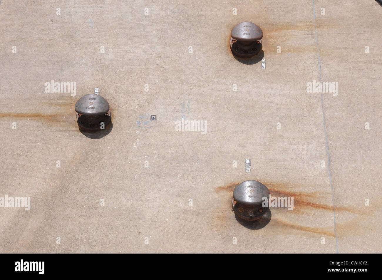 Three capstans on concrete dock, rust marks, mooring, aerial view Stock