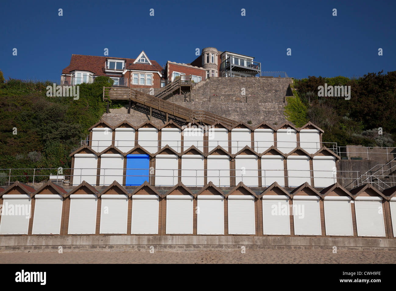 Three levels of Beach huts with white roller shutter doors and one blue door (digitally created) Stock Photo