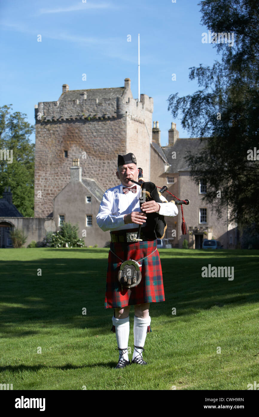 scottish bagpipe player playing pipes in front of kilravock castle