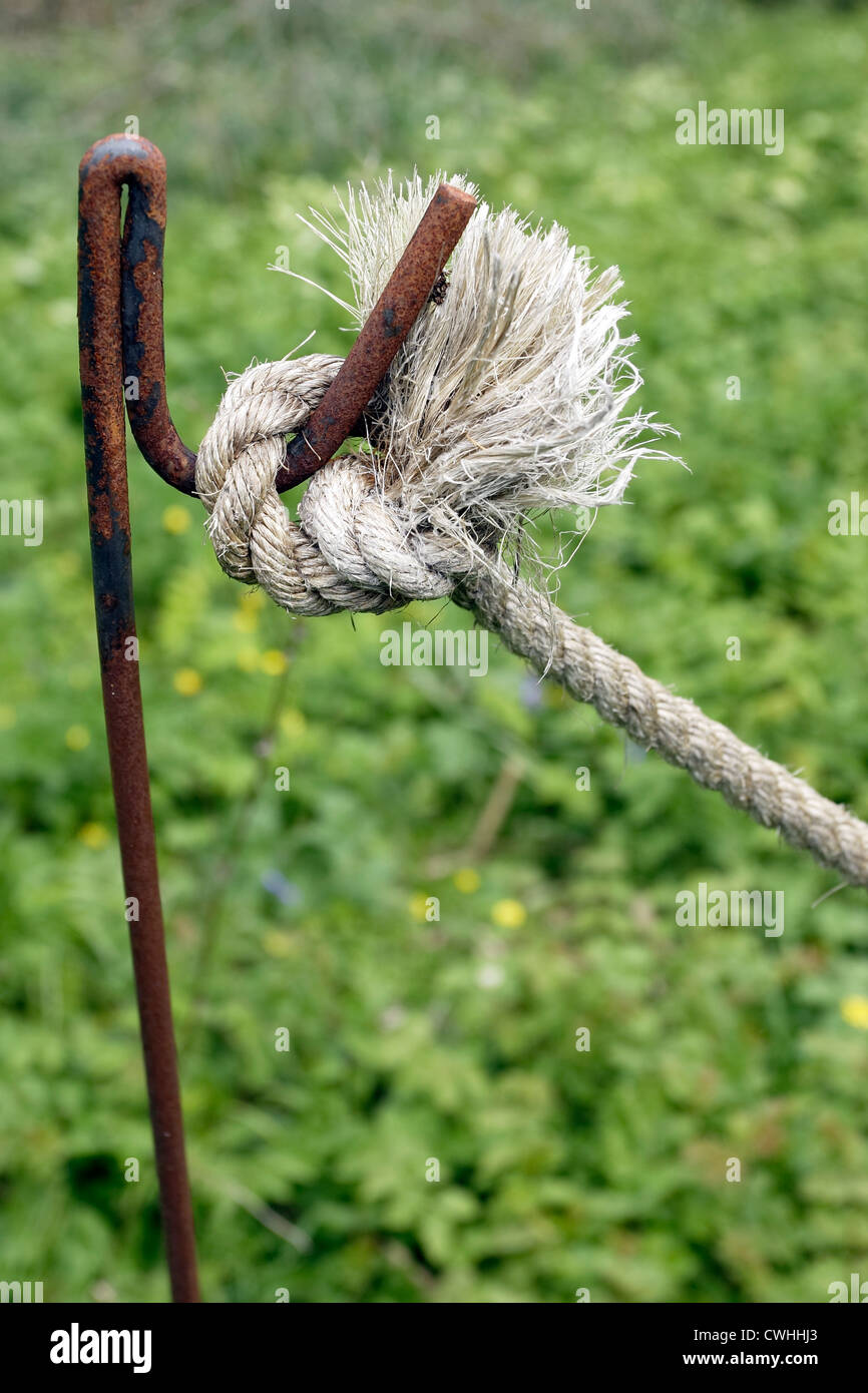 A rope knotted around an iron stanchion, marking an area boundary. Stock Photo
