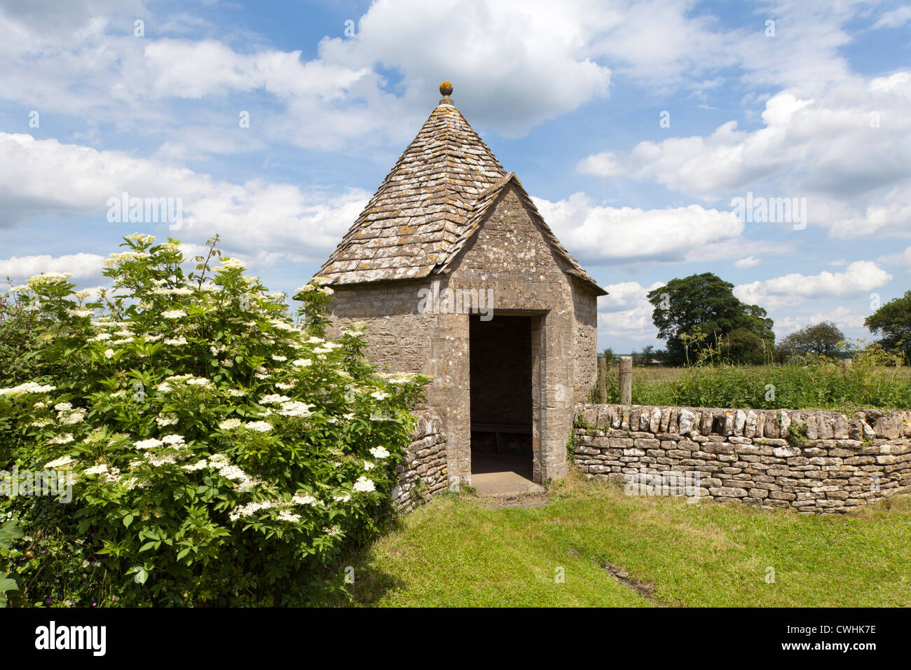 A delightfully quirky octagonal bus shelter built of Cotswold stone in the Cotswold village of Farmington, Gloucestershire, UK Stock Photo