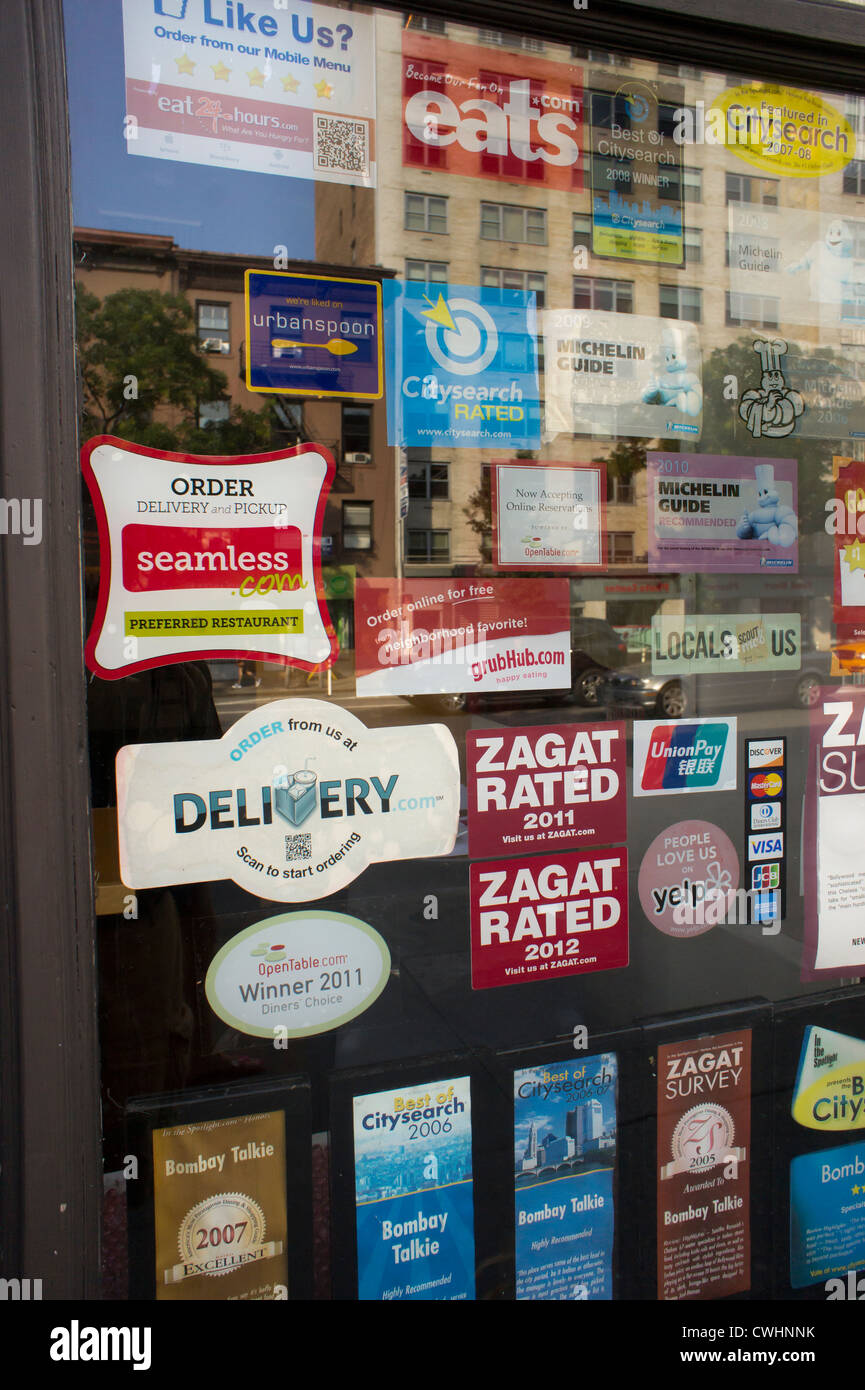 Stickers promoting various crowdsourcing review sites and delivery services are seen on the door of a restaurant Stock Photo