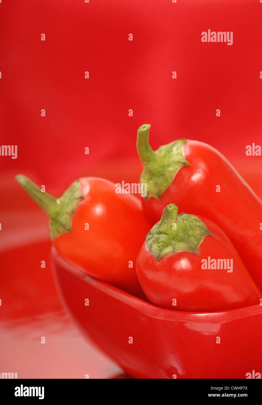 Red chili peppers in a red bowl with a red background Stock Photo - Alamy