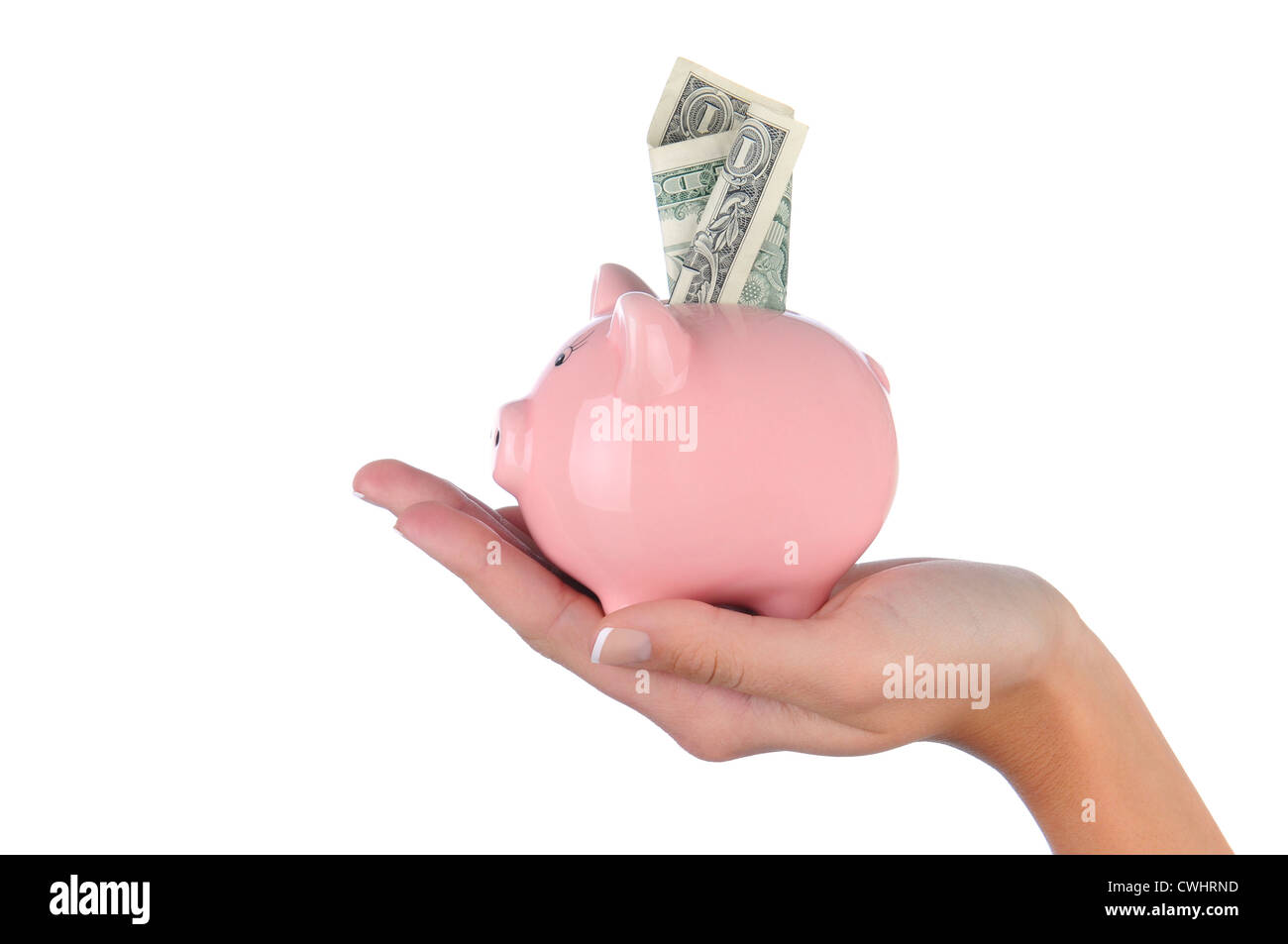 Closeup of a woman's hand holding a pink piggy bank with a dollar bill stuck in the top slot. Stock Photo