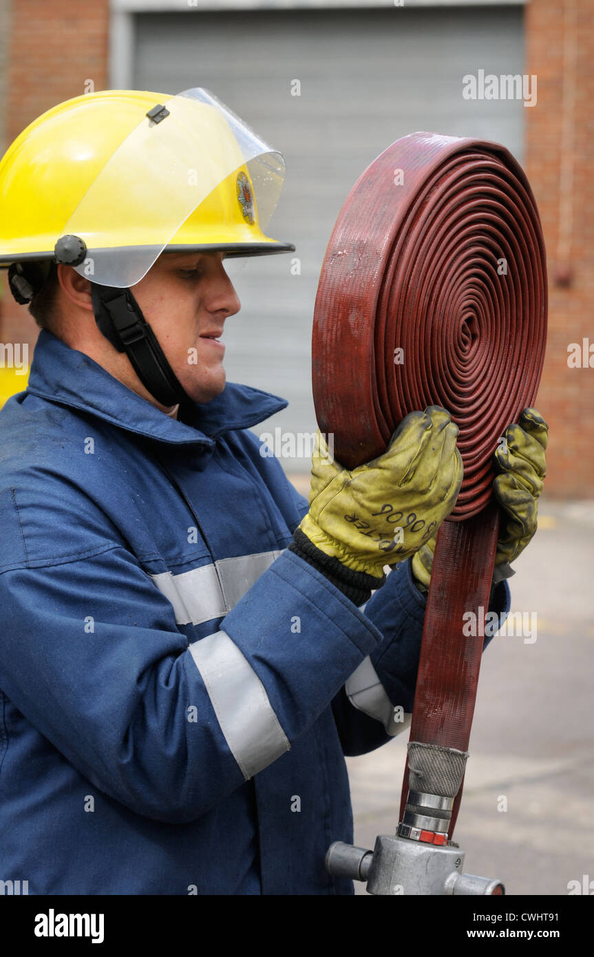 A fireman coiling up a hose during an exercise with white watch at Pontypridd Fire Station in South Wales UK Stock Photo