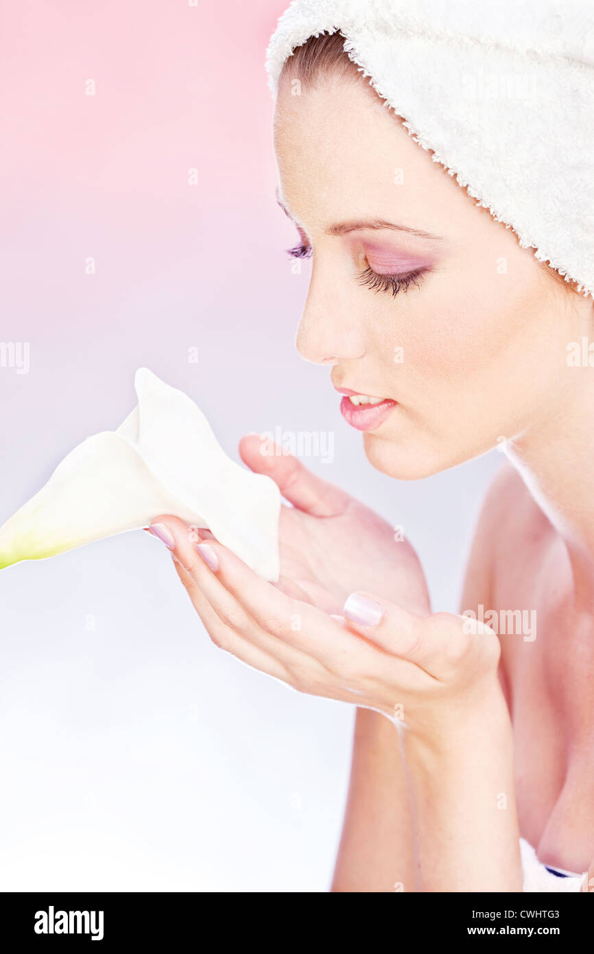 pretty woman with towel on head gently holding a white flower Stock Photo