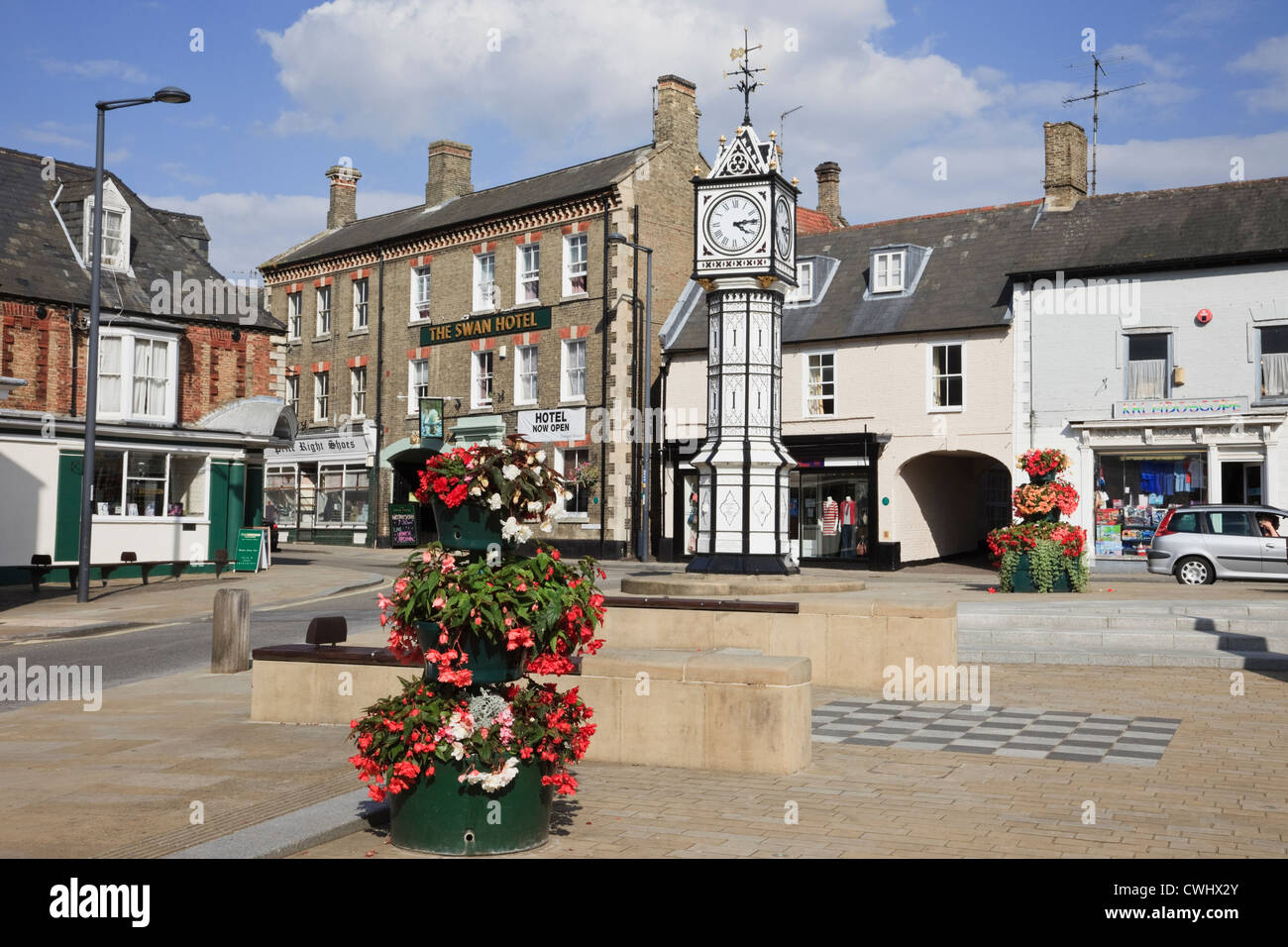 Shops around the paved town square with ornate old clock by James Scott by Swan hotel in Downham Market, Norfolk, England, UK Stock Photo