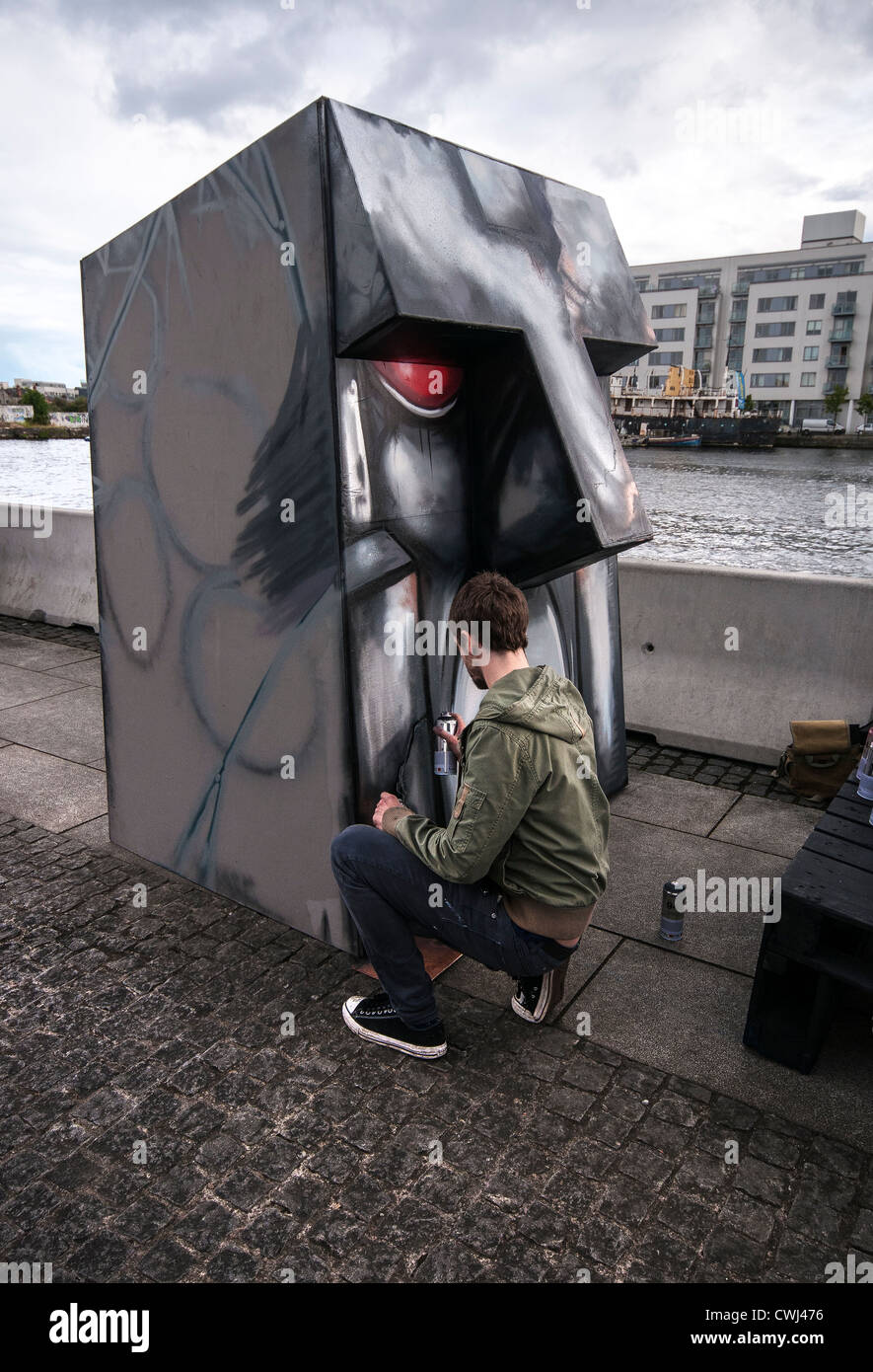 Graffiti artist spraying sculpture on Grand Canal Square in Dublin, Ireland Stock Photo
