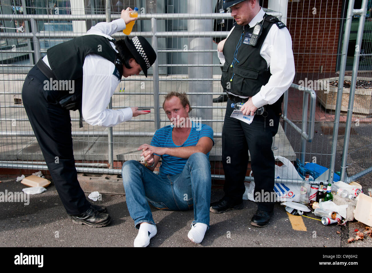 Young man who overdid alcohol & partying at Notting Hill Carnival celebrations questioned & helped by police Stock Photo