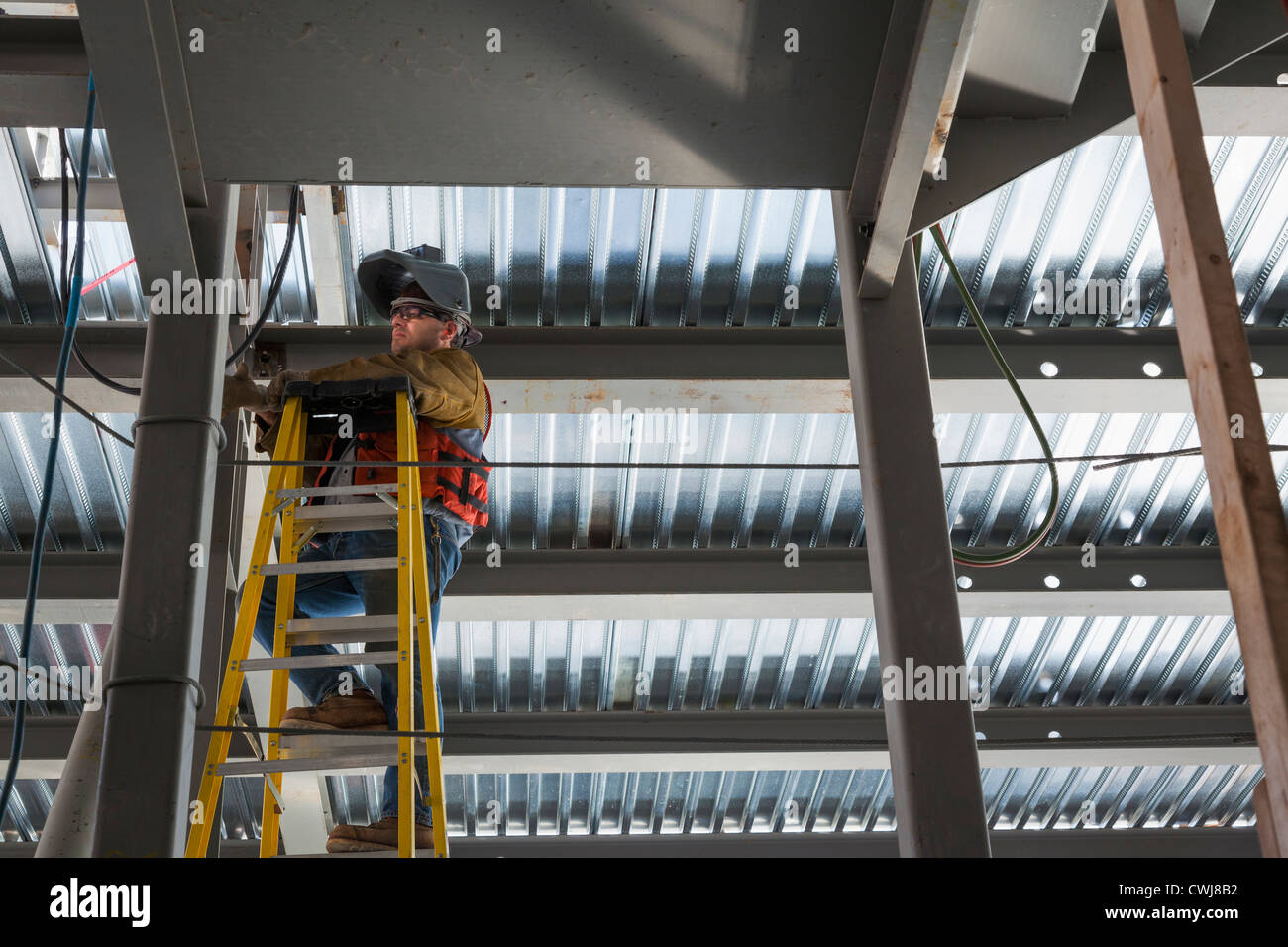 Caucasian construction worker standing on ladder Stock Photo