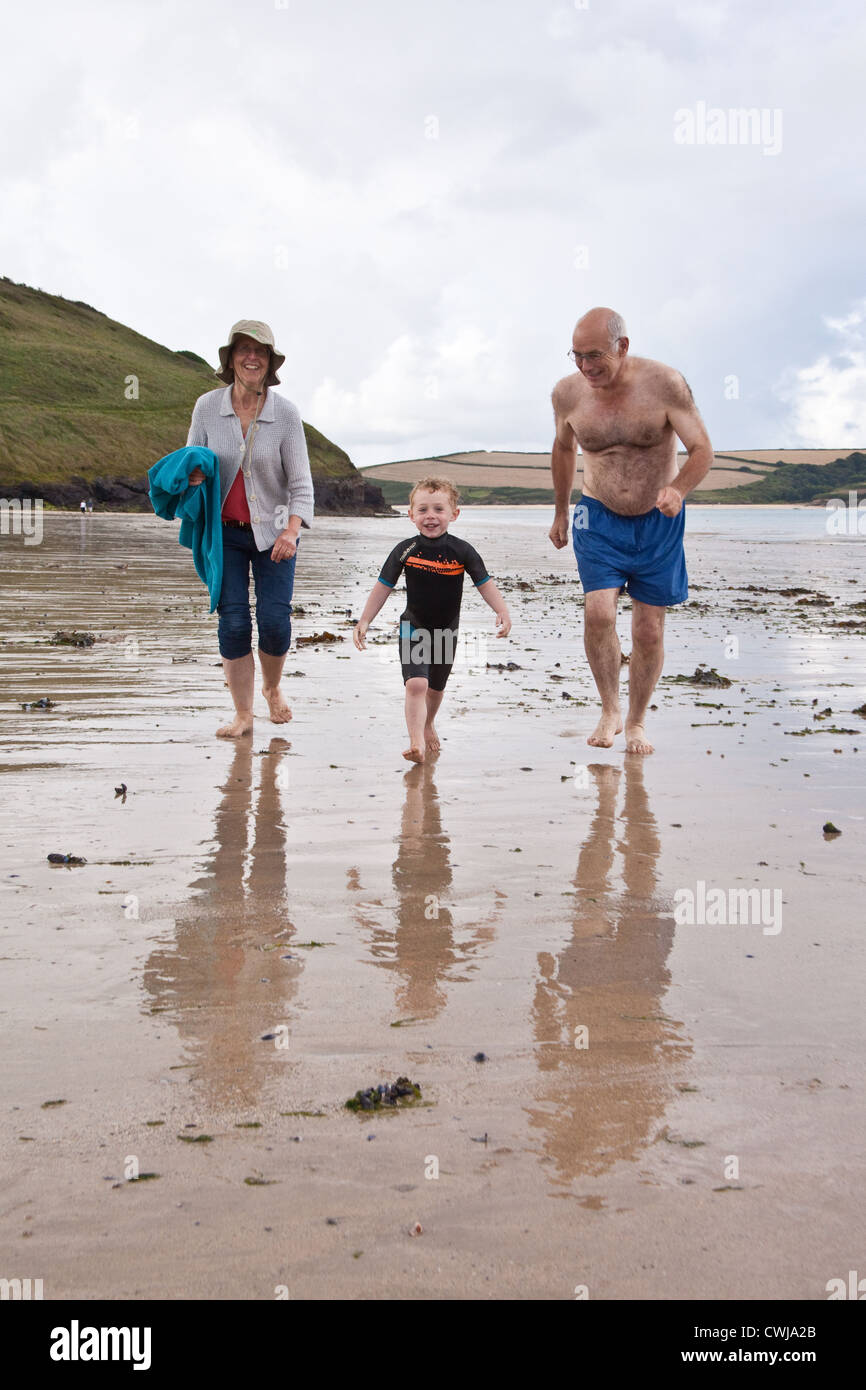 Three year old boy with his grandparents on Daymer bay beach near Rock, Cornwall, England, United Kingdom. Stock Photo