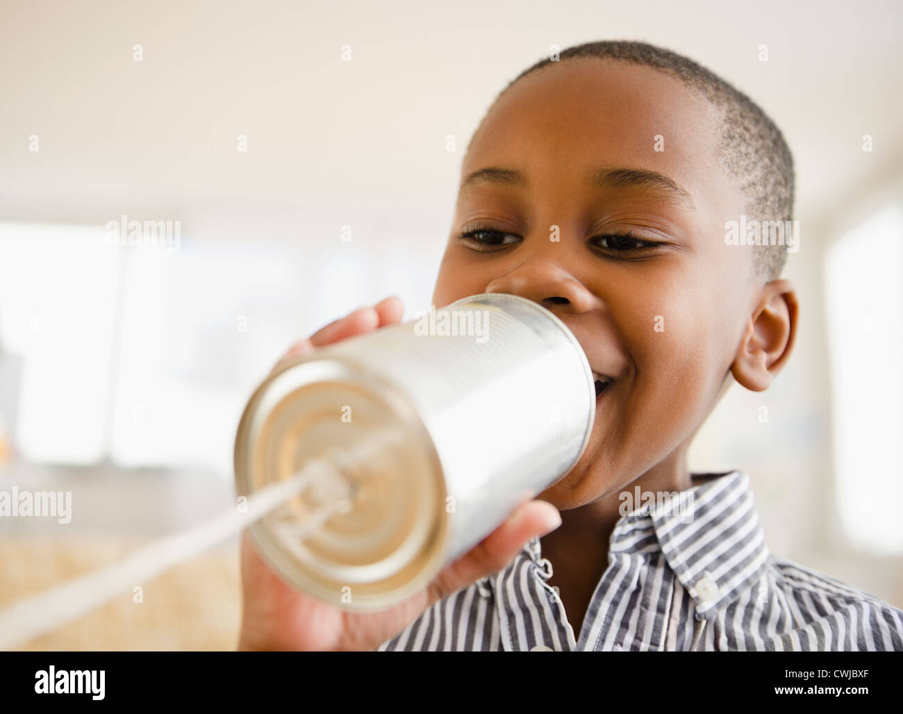 Black boy talking into tin can phone Stock Photo