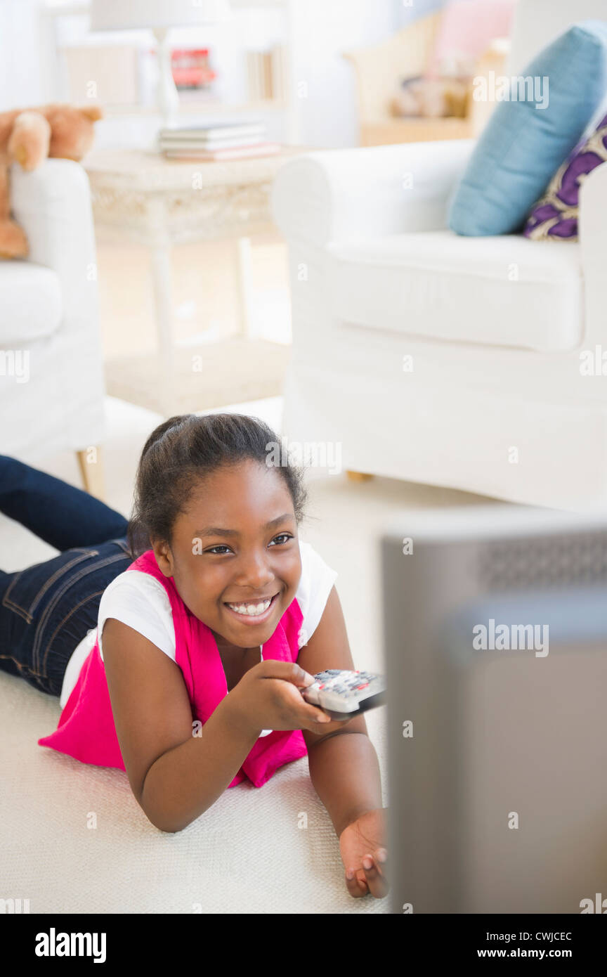 Black girl laying on floor watching television Stock Photo
