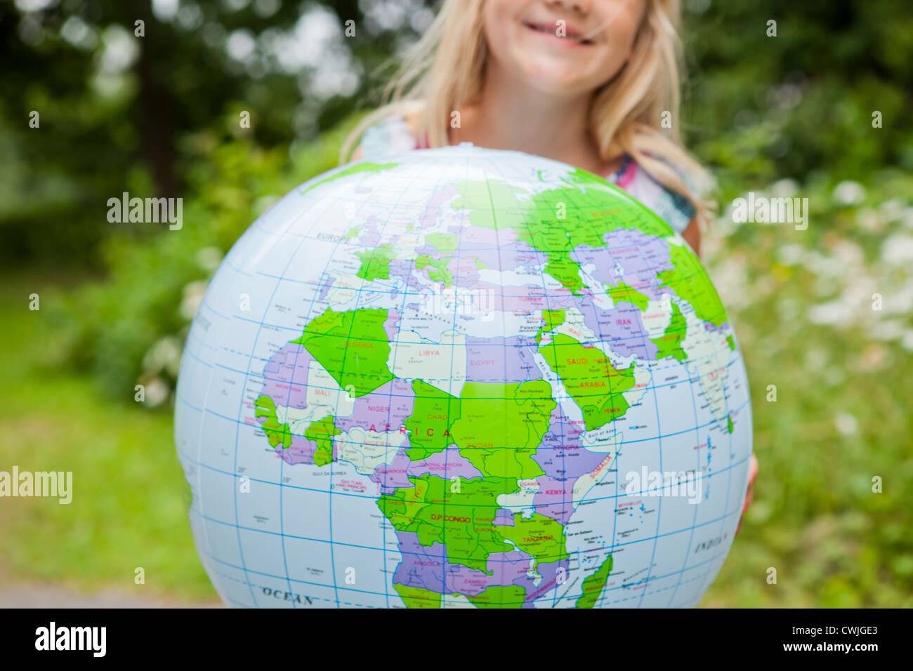 Little girl holding a colorful earth globe outdoors Stock Photo