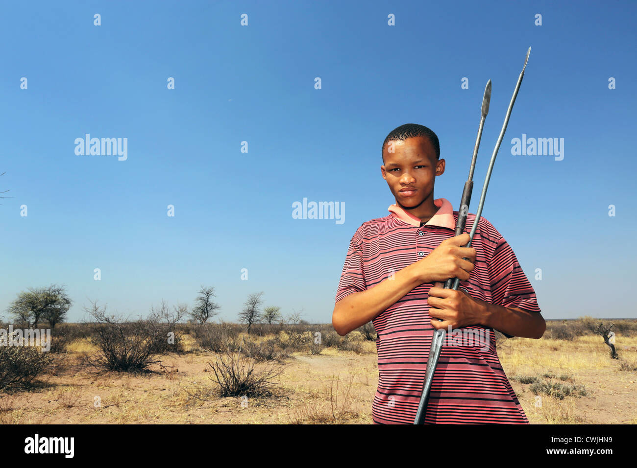 Boy of the indigenous San tribe with spears, Namibia, Kalahari desert Stock Photo