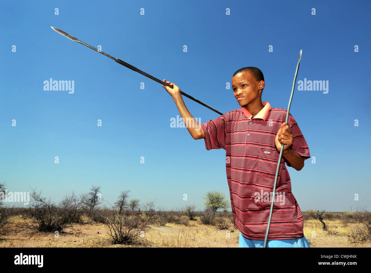Boy of the indigenous San tribe throws a spear, Namibia, Kalahari desert Stock Photo