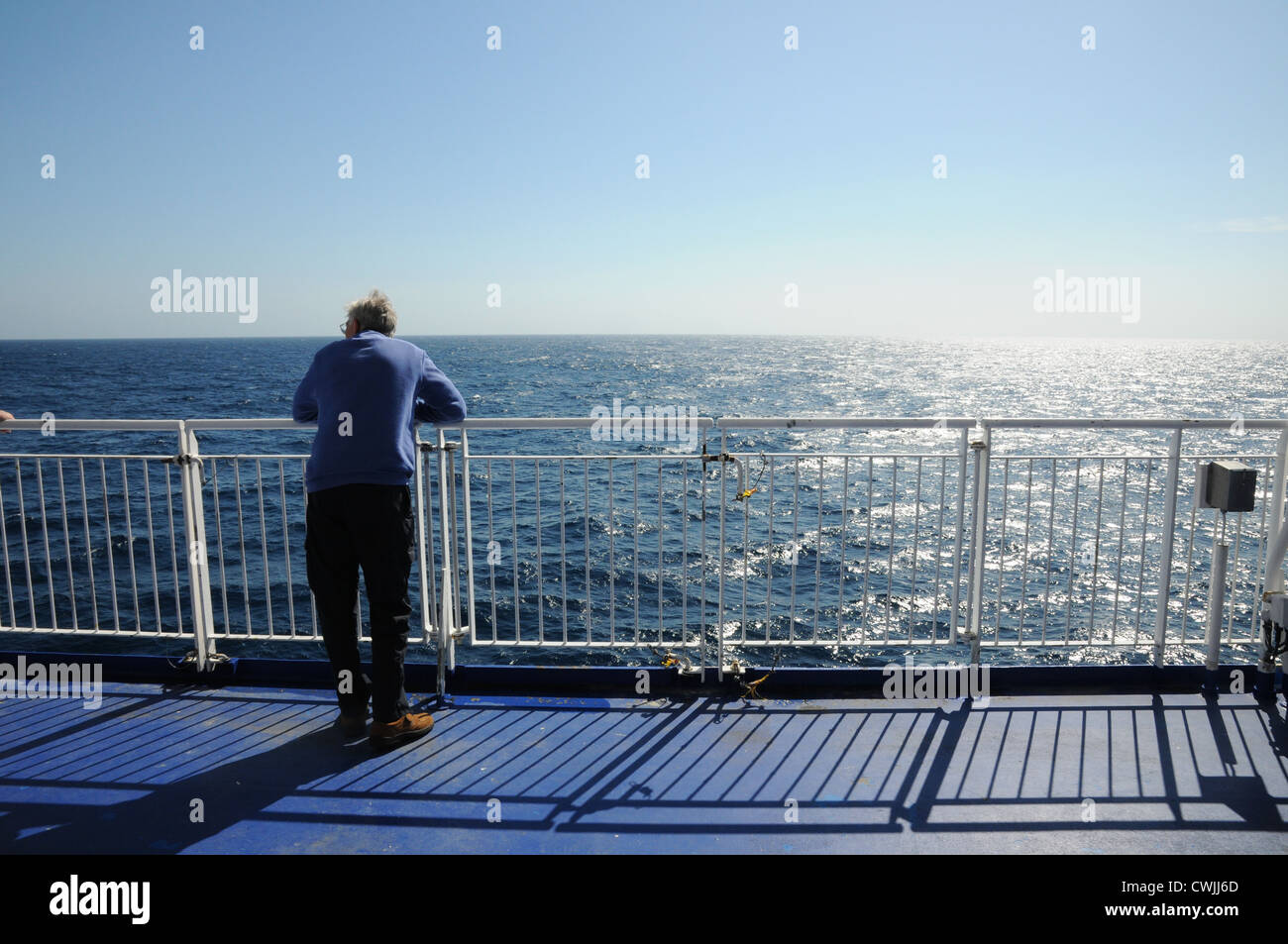 Rear of one man, wearing sweater, leaning on guardrail, whale watching ...