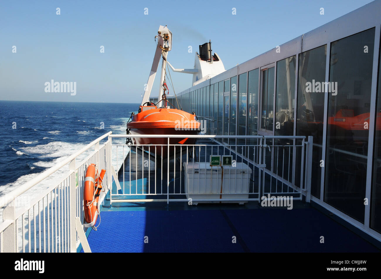 View down starboard side, to stern of Cap Finistere cruise ferry, showing lifeboat, funnel, calm blue sea, Bay of Biscay. Stock Photo