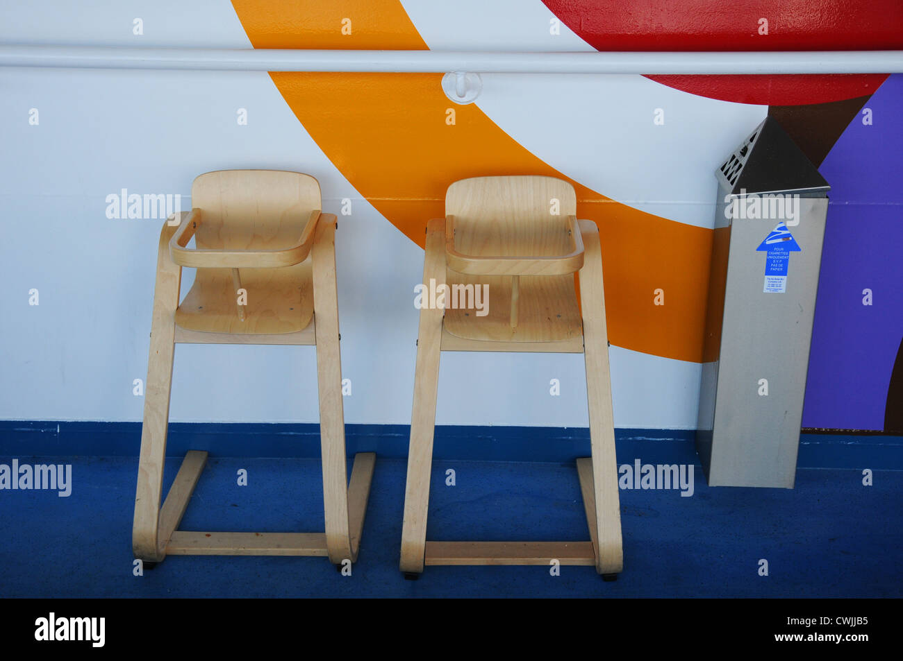 Two wooden high chairs, next to ash dispenser on cruise ferry deck