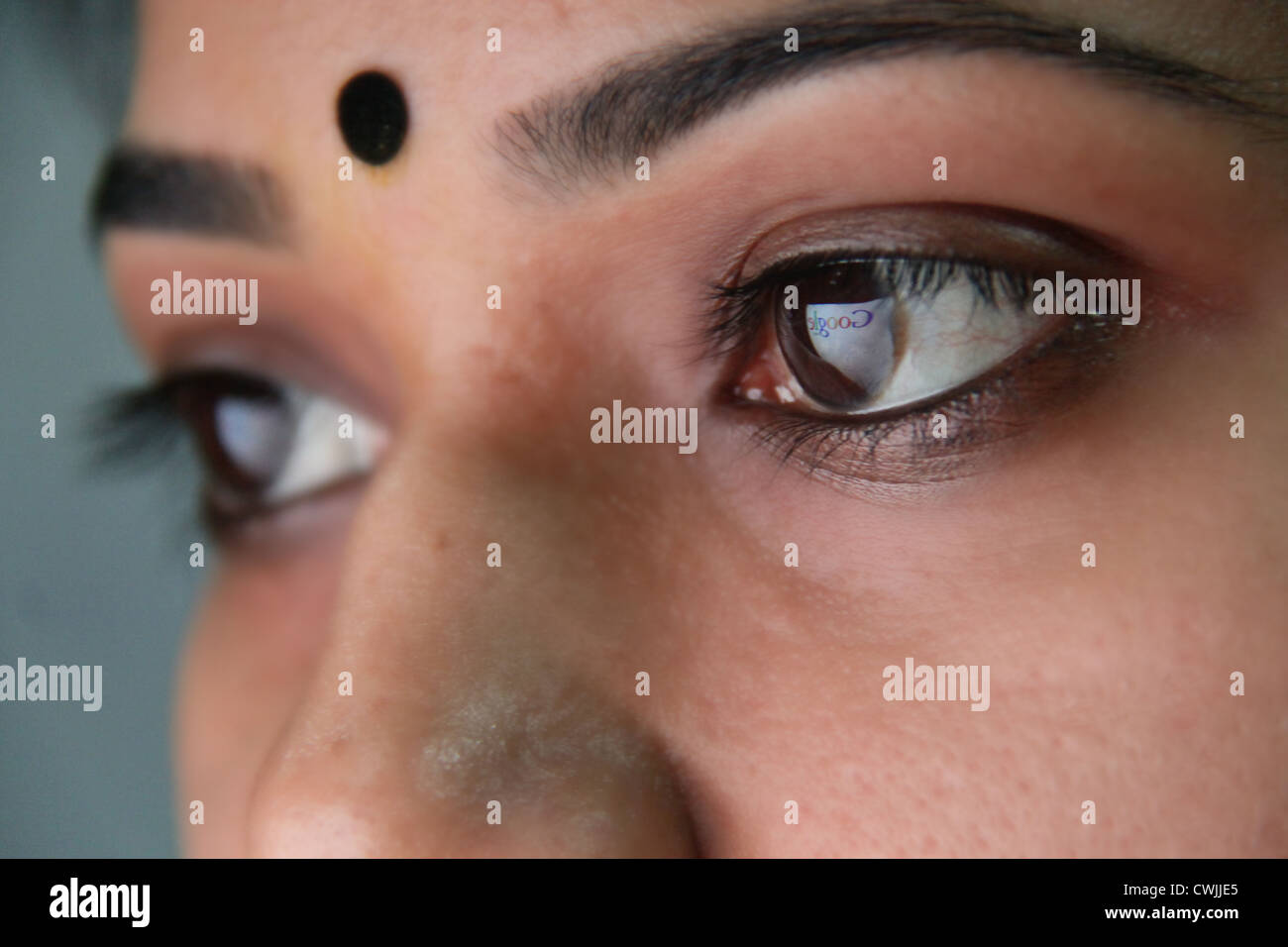 Beautiful Indian woman searching in Google, reflection of website in her eyes Stock Photo