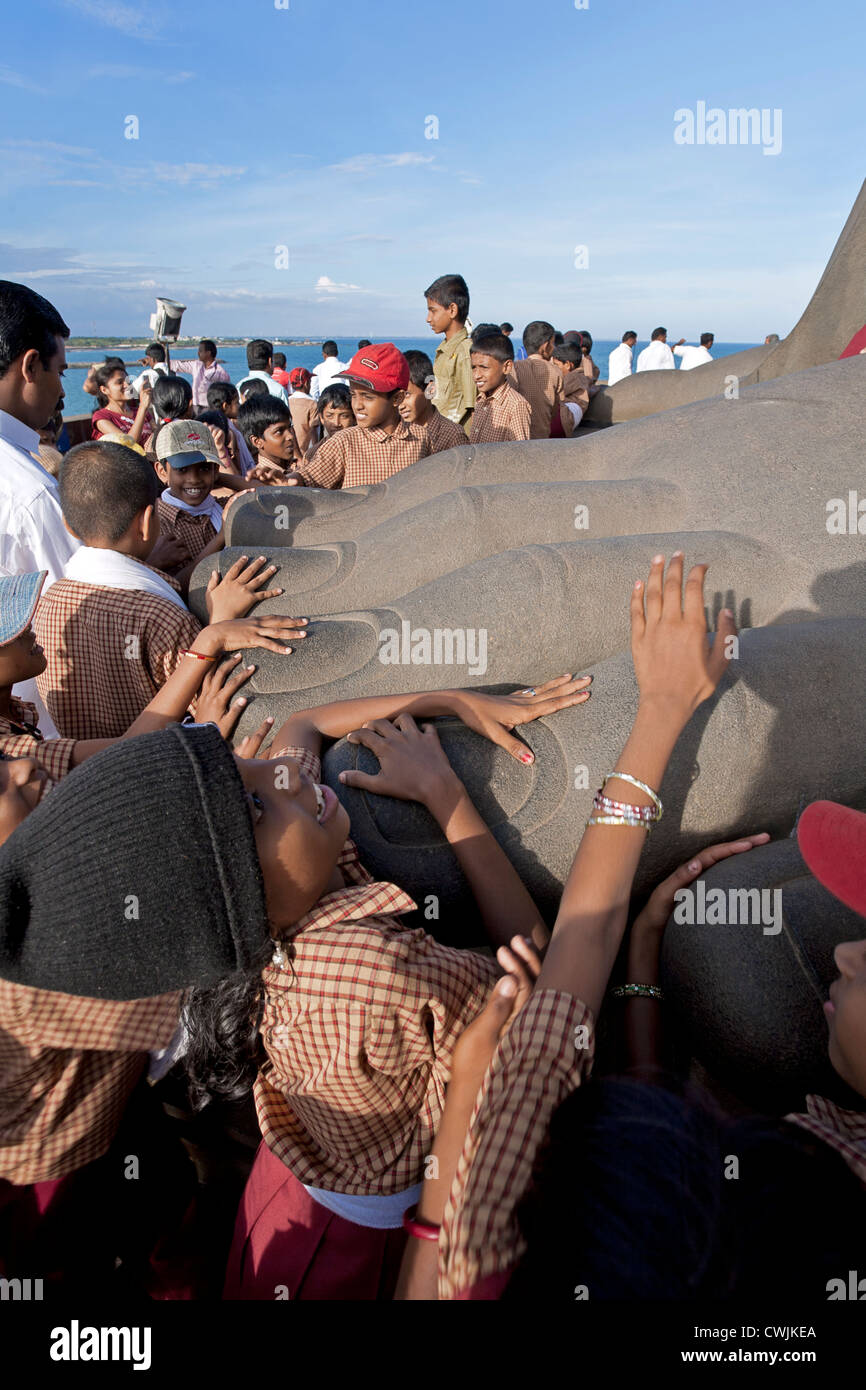 Kids touching the toes of the huge Thiruvalluvar statue (Indian poet). Kanyakumari. India Stock Photo