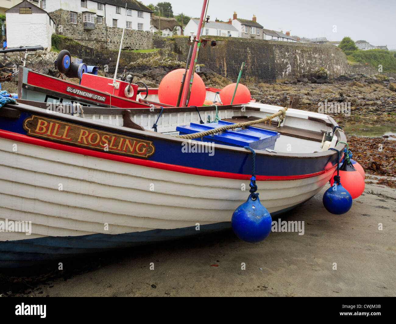 Traditional Cornish fishing boat with village in background Stock Photo