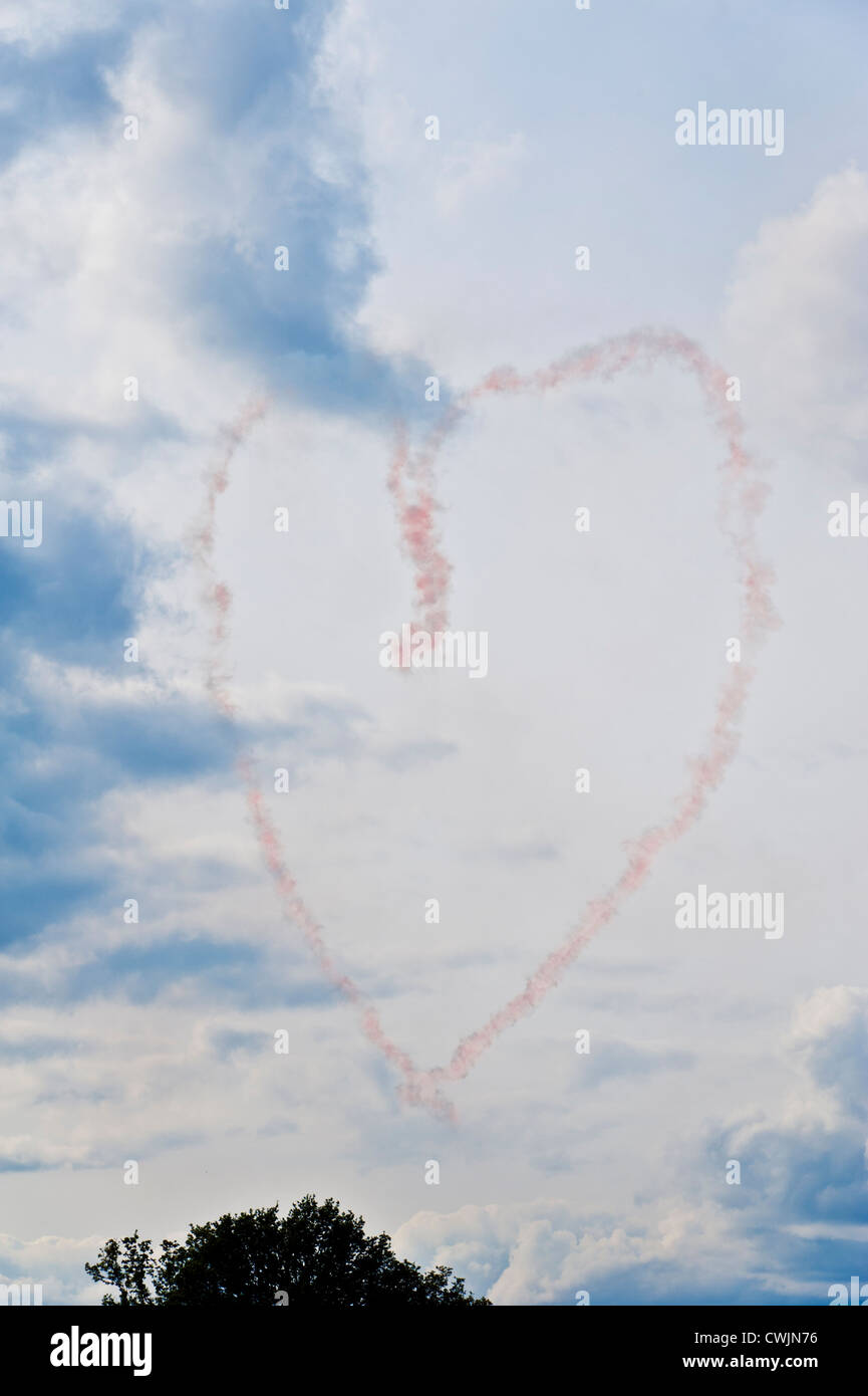 Pink smoke trails from an aerial aerobatics display team forming a love heart symbol in the sky. Concept image Stock Photo