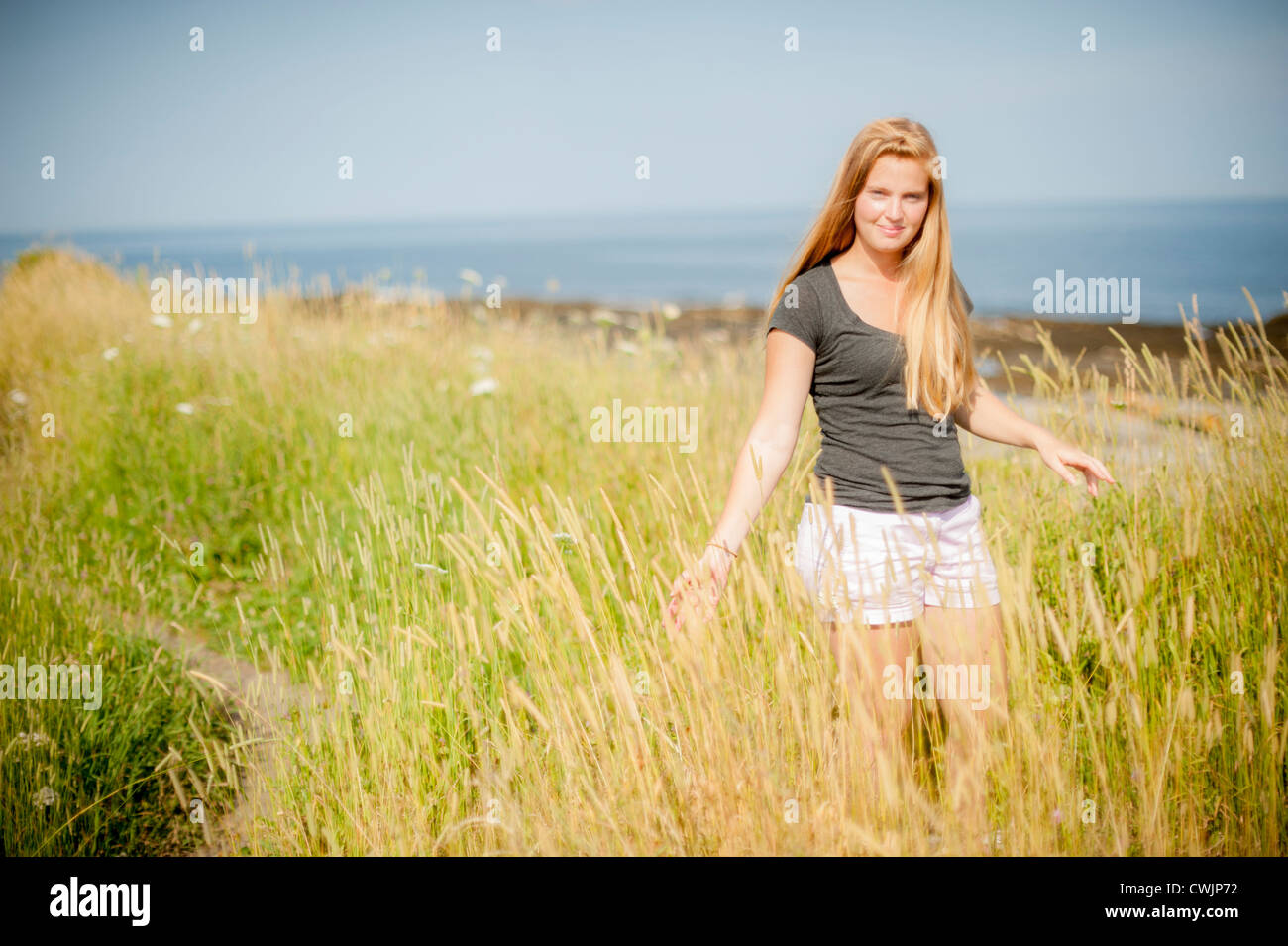 Blonde Woman in wind swept dunes, Cape Elizabeth Maine USA Stock Photo